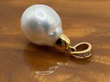 a white pearl and a gold ring on a wooden table