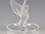 un oiseau en verre posé sur une assiette en verre