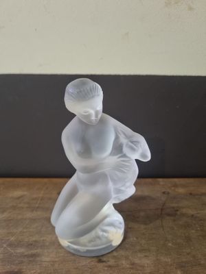 a glass figurine of a woman sitting on a table