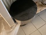 un tabouret noir au milieu d'un sol carrelé