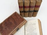 several old books are stacked on top of each other on a white surface
