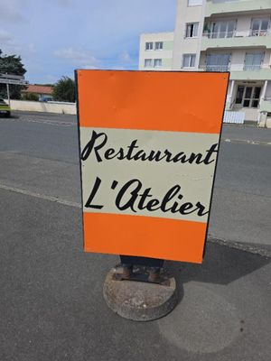 une enseigne indiquant « Restaurant L'Atelier » au bord de la route