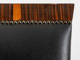 the back of a black leather chair with a wood trim