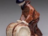 figurine of a man sitting on a barrel with a hat on