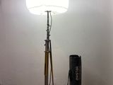 une lampe posée sur un trépied à côté d'un sac