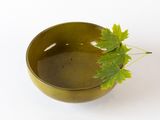 a small green plant in a brown bowl on a white surface