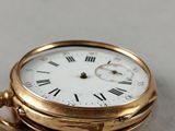 a gold pocket watch with roman numerals on it