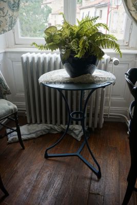 une petite table sur laquelle se trouve une plante en pot, devant une fenêtre