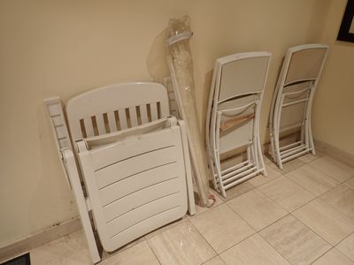 quatre chaises dans un coin d'une pièce où est accroché un ventilateur au mur