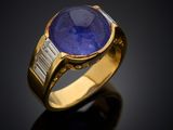 a gold ring with a blue stone and baguets