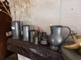 many silver vases on a wooden shelf next to a vase