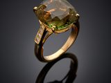 a close up of a ring with a green stone and diamonds