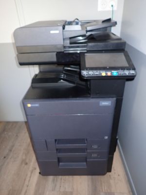 a multi - function printer sitting on top of a black cabinet