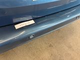 the rear end of a blue car with a sticker on it