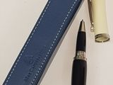blue leather pen case with a black ballpoint pen sitting next to it