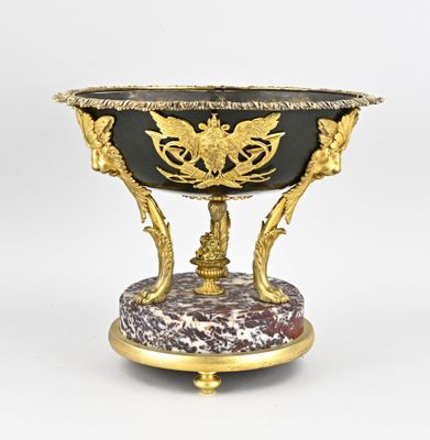 une image représentant un vase noir et doré posé sur un socle