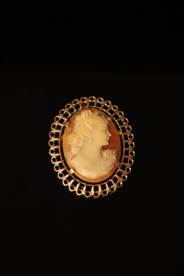 a close up of a gold plated broocher with a woman ' s face