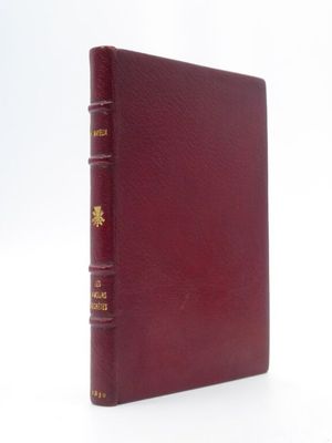 un vieux livre à la couverture rouge posé sur une surface blanche