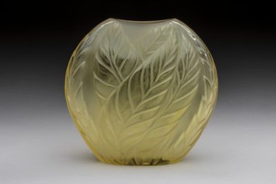 un vase en verre jaune orné d'un motif de feuilles