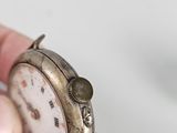 a person holding a small silver pocket watch in their hand