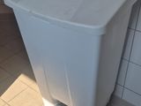 une poubelle blanche posée par terre dans une salle de bains