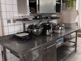 une grande cuisine avec de nombreux plans de travail en inox