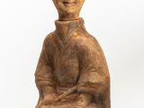 statue of a woman sitting on a rock with a hat on her head