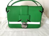 un sac à main Longchamp vert posé sur une nappe blanche