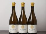 trois bouteilles de vin sont alignées sur une table en bois
