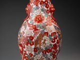 an orange and white vase with flowers on it on a gray surface
