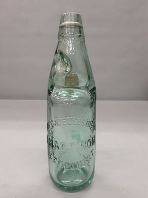une bouteille en verre vert avec un bouchon argenté, posée sur une table