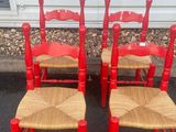 three red chairs with wicker seats sit in front of a building