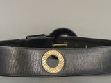 black leather belt with a gold buckle on a gray surface