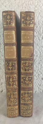 une paire de livres anciens reliés en cuir posés sur une surface blanche