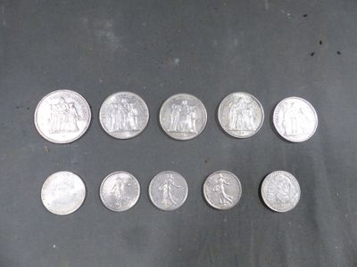 Plusieurs pièces d'argent de 25 centimes sont alignées sur une table