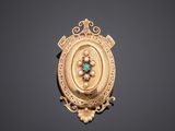 a gold broochle with a turquoise and white stone in the center