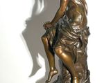 bronze statue of a woman sitting on a rock with her legs crossed