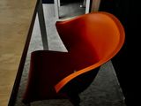 une chaise orange posée devant une table en bois