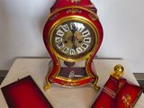une horloge rouge et dorée posée sur une table