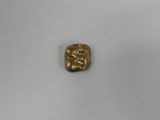 a gold plate with a small square shaped object on top of it