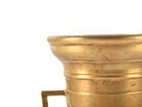 a gold vase that is on a stand on a white surface