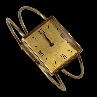 une image d'une montre en or avec des chiffres romains sur le cadran