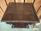 an old wooden table with a carved top on a carpeted floor