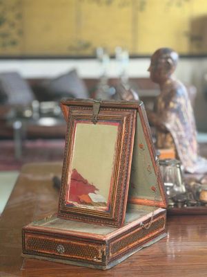 a picture frame on a table with a figurine in the background