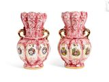 une paire de vases roses et blancs avec des anses dorées sur fond blanc