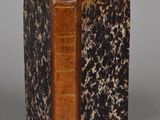 an old book sitting on top of a table next to a gray wall