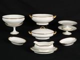 a group of white and gold dishes on a black background