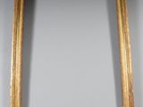an antique gold frame with a mirror on the wall