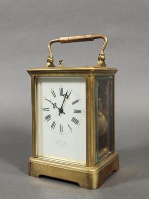 une petite horloge en laiton avec des chiffres romains sur le cadran