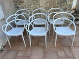 four white chairs sitting in front of a stone wall